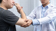 © Ngampol - Young asian physiotherapist giving assistance to man patient with elbow injury