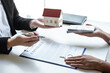 © Ngampol - Estate agent sending house model to client after signing agreement contract real estate with approved mortgage application form, concerning mortgage loan offer for and house insurance