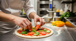 © Aksaka - Chef's hands topping pizza with fresh vegetables