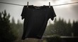 © Langit2 - A black t-shirt hangs on a clothesline in the rain, against a blurred forest backdrop on a gloomy day