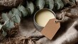 © ColorSpire - A pale yellow balm in a silver tin sits on burlap, adorned with a blank tag and eucalyptus sprigs