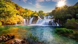 outstanding vertical picture of a waterfall surrounded by greenery under the sunlight in krka