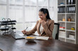 © Apichat - Businesswoman eating potato chips while working on laptop in office