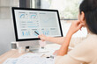 © kenchiro168 - Woman pointing at desktop monitor displaying business analytics dashboard with charts and graphs, focused team collaboration and planning, productive office scene, soft natural light