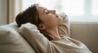 © Assetian - Woman relaxing on the couch with her eyes closed in a peaceful state of mind