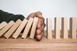 © Dadan - male hand stop falling wooden blocks. domino effect or risk protection strategy concept