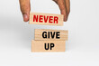 © Dadan - male hand put wooden blocks with never give up words text isolated on white background. motivational quote concept