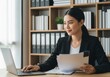 © BD ISLAM - Focused businesswoman working diligently on her laptop with documents in a well organized office setting