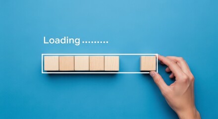 Loading bar with wooden blocks being completed by a hand on a blue background
