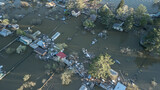 Aerial drone footage showing severe flooding with submerged houses and roads. Wide overhead view of a disaster zone after heavy rainfall, showcasing water damage, extreme weather, and climate-related 