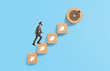 © ImageFlow - Businessman climbing wooden blocks with arrows toward target ico