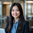© 시로K - Young Asian female employee looking at the camera with a positive smile in an office setting