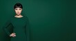 © Desg man - Elegant asian woman in a sophisticated green dress, posing confidently with hand on hip against a deep green background, embodying modern chic