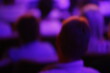 © Pascal Huot - Image floue d'un groupe de personnes dans une salle de conférence.