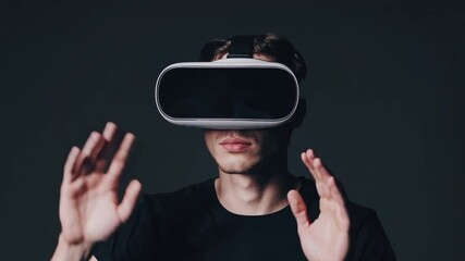 Caucasian male utilizing see-through digital display device worn on the head, set against solid dark backdrop