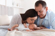© New Africa - Mom and dad with their newborn baby on bed at home
