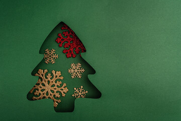 Wall Mural - red baubles, bells, and a glitter snowflake arranged inside a green paper christmas tree cutout, cre