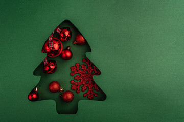 Wall Mural - red baubles, bells, and a glitter snowflake arranged inside a green paper christmas tree cutout, cre