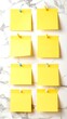 © Iyat - Nine blank yellow sticky notes affixed to a white marble surface, showcasing a clean and organized design.