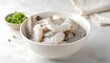 © Zania - Fresh shrimp in a white bowl, ready for cooking, set against a light gray surface.