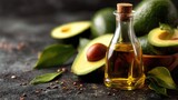 Golden Avocado Oil in Glass Bottle with Halved Avocados on Dark Counter.