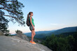 © bilanol - Young woman hiker standing alone on mountain footpath enjoying view of evening nature on wilderness trail. Active way of life concept