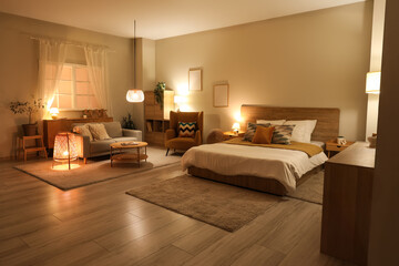 Wall Mural - Stylish interior of bedroom with comfortable armchair and bed at evening