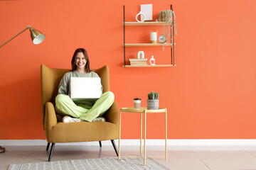 Poster - young woman using laptop in armchair at home