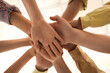 © Pixel-Shot - Young people putting hands together at group therapy session, bottom view