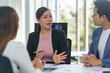 © Crystal - Asian businesspeople discussing during a meeting in a modern office, analyzing financial charts and graphs