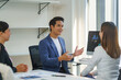 © Crystal - Asian businessman leading a meeting explaining strategy to colleagues in the office using a computer, teamwork and business concept