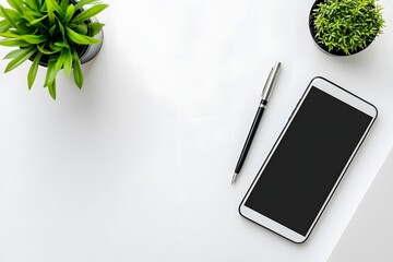 top view of minimalist white desk with smartphone, pen, and single green plant 
