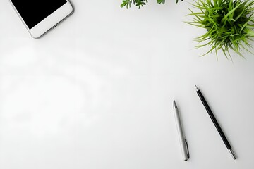 top view of minimalist white desk with smartphone, pen, and single green plant 
