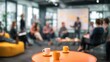 © Arpatsara - A blurred image of a group meeting with two cups of coffee on an orange table, highlighting collaboration and creativity in a modern workspace.