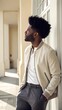 © Tatimurmurprint - Pensive Black man with afro hairstyle leaning against a white building wall looking up in sunlight