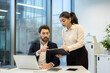 © Liubomir - Business colleagues discussing a project using laptop and clipboard in office
