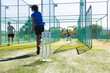 © Wavebreak Media - Diverse male teammates practicing bowling, batting on artificial turf in cricket net with stumps