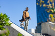 © Wavebreak Media - African american man walking on plaza steps carrying skateboard, backpack wearing headphones