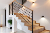 Schody drewniane z czarną balustradą – nowoczesne jasne wnętrze z rośliną