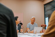 © Johnér - Mature businesswoman sitting with laptop while discussing ideas in office meeting