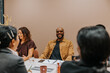 © Johnér - Smiling bald businessman sitting with colleagues at table in office board room