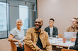 © Johnér - Happy bald businessman sitting with colleagues in meeting room at office