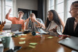 © Johnér - Male business employees reacting on female colleague spilling coffee on table in meeting room