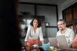 © Johnér - Mature female business expert bending on table while planning strategies in meeting with coworkers at office board room