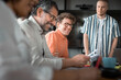 © Johnér - Happy male business expert wearing eyeglasses sitting with coworkers in office meeting