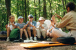 © standret - Survival tips, sitting at camp. Woman is doing tour for group of kids in the forest