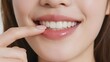 © jiale - Close-up of a person gently touching their lower lip, showcasing a bright smile with white teeth.