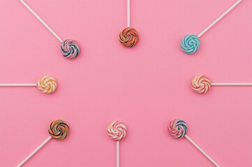 Wall Mural - colorful lollipops in bright and soft shades arranged perpendicularly on a pink surface