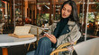 © shine.graphics - Young woman in trench coat sitting at outdoor cafe table with vintage book and smartphone. Autumn mood with elegant style and cozy ambience