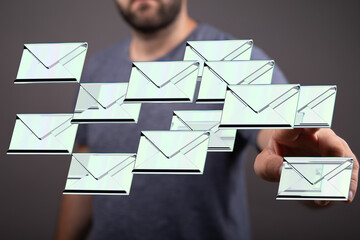 Stock photo of a man interacting with a digital interface displaying a stream of email messages, symbolizing email management or communication.